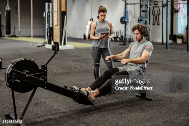 exercising on rowing machine - personal trainer stock pictures, royalty-free photos & images