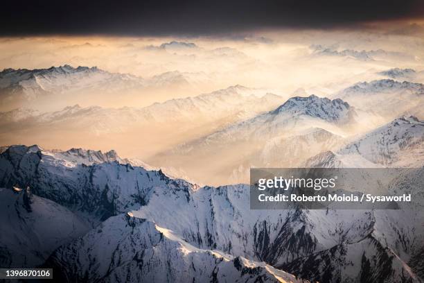 sun rays in the foggy sky at sunset over the swiss alps - luftaufnahme schweiz stock-fotos und bilder