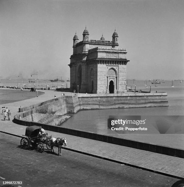 Pedestrians and a horse and cart in front of the Gateway of India, an arch-monument in the city of Bombay in India during World War II circa March...