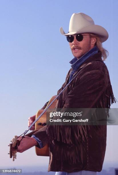 American Country musician Alan Jackson plays an acoustic guitar during the filming of a music video, for his song 'Gone Country' , on a midtown...