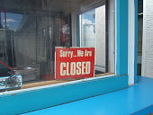 A red closed sign in the window of a blue building