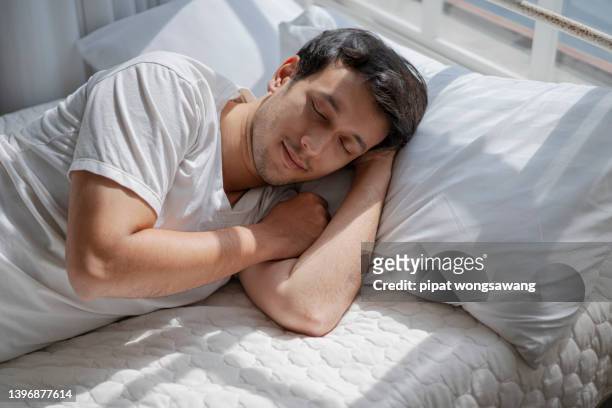 the man was sleeping soundly in bed even though it was late. - sleeping man stock pictures, royalty-free photos & images