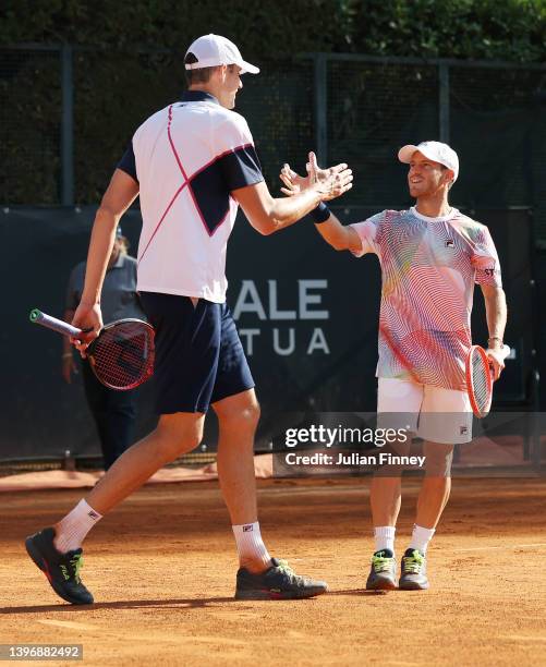 John Isner of the United States and Diego Schwartzman of Argentina shake hands during their Men's Doubles Round 2 match against Juan Sebastian Cabal...