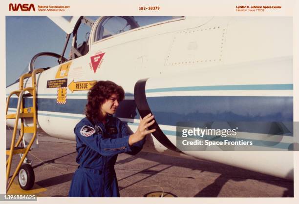 American astronaut and physicist Sally Ride , STS-7 mission specialist, checks over a T-30 jet aircraft on the flight line at Ellington Air Force...