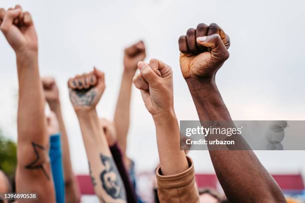 manifestantes levantando puños - clenched fist fotografías e imágenes de stock