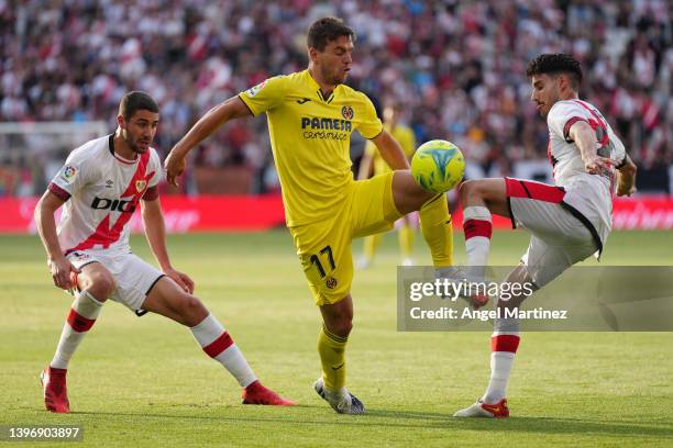 Giovani Lo Celso of Villarreal CF is challenged by Oscar Valentin of Rayo Vallecano during the La Liga Santander match between Rayo Vallecano and...