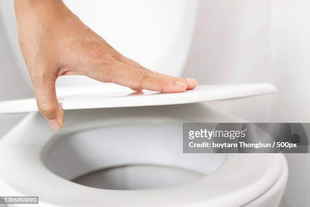 womans hand opening the toilet lid - losbreken stockfoto's en -beelden