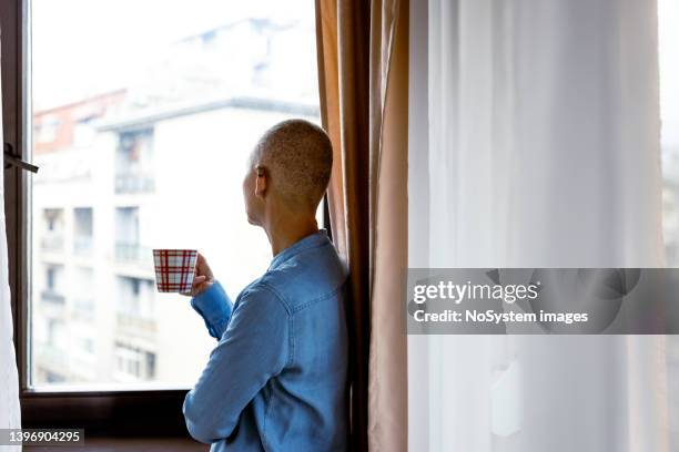 woman living with cancer - looking through window covid stock pictures, royalty-free photos & images