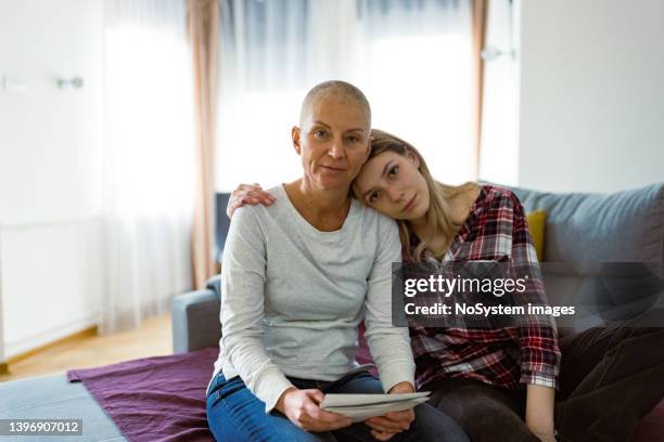 woman with cancer and her daughter browsing family photos - woman home with sick children stock pictures, royalty-free photos & images