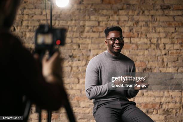 junger mann gibt ein interview in einem studio - interview gespräch stock-fotos und bilder