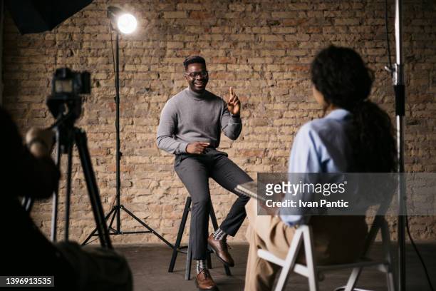 journalistin interviewt einen gutaussehenden jungen mann - african american interview stock-fotos und bilder