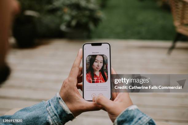 a man holds a smart phone and browses a dating app - hand holding phone stock pictures, royalty-free photos & images