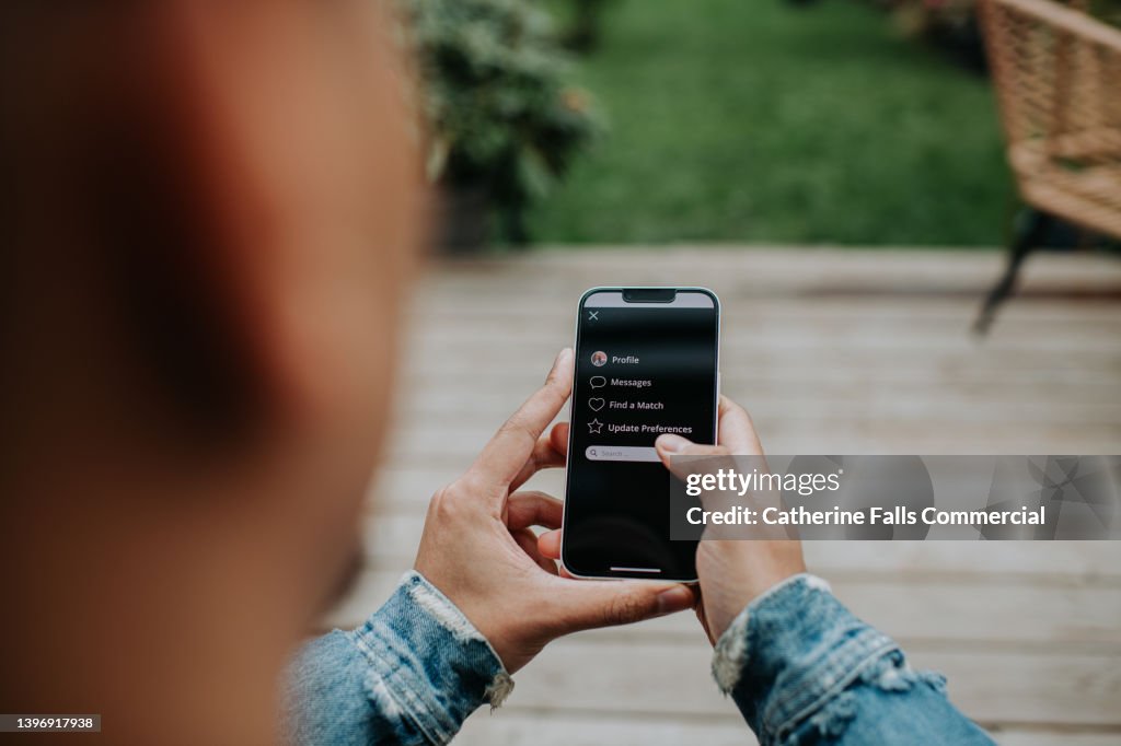 A man holds a smart phone and browses a dating app with a simple user-friendly interface