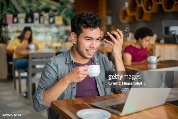 man at a cafe listening to a voice message on his cell phone - coffee chat stockfoto's en -beelden