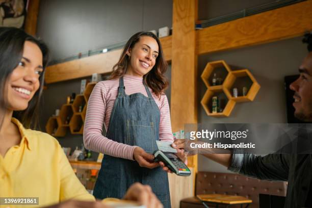 man making a contactless payment to the waitress at a restaurant - card reader stockfoto's en -beelden