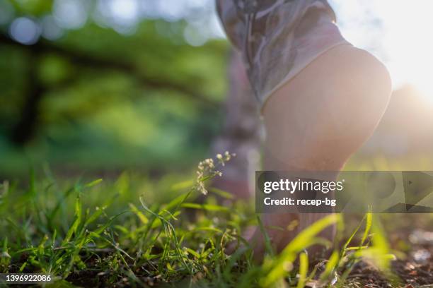 foto de close-up dos pés descalços de uma mulher enquanto caminhava sobre grama e solo na natureza - descalço - fotografias e filmes do acervo