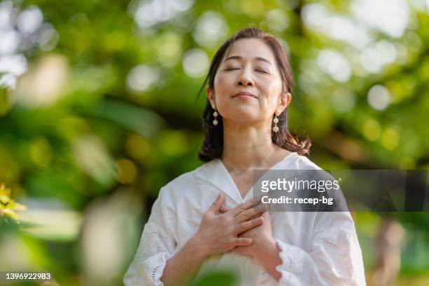 自然の中で瞑想する女性 - 胸に手を当てる �ストックフォトと画像