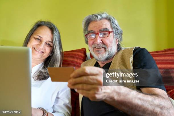 happy active couple of adult seniors togetherness looking down with card - pensioners demonstrate in spain stock pictures, royalty-free photos & images