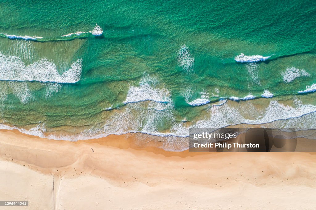 Pristine clear water ocean waves rolling onto golden sandy beach