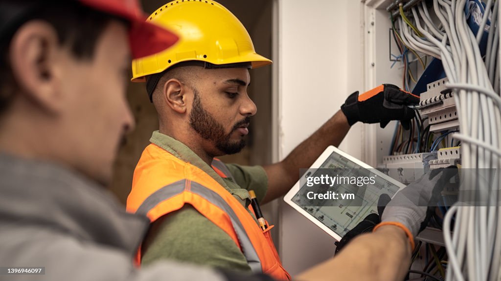 Drawings displayed on digital tablet, professionals testing switchboard