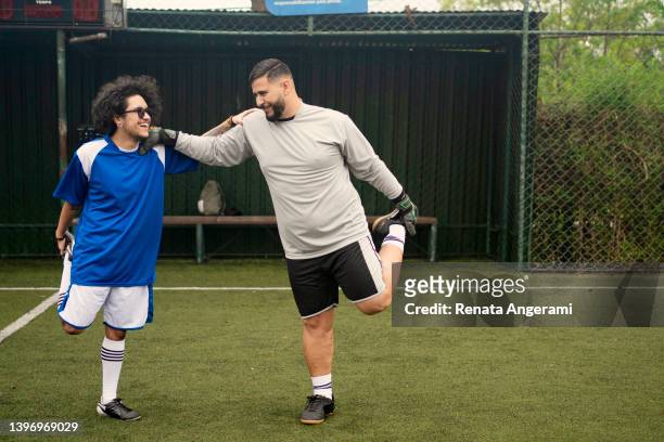 transgender male soccer player and his friend warming up on the field - sunday league stock pictures, royalty-free photos & images
