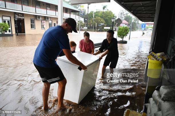 Locals help a Chinese restaurant owner as he tries to salvage a freezer as floodwater inundate his business on May 13, 2022 in Laidley, Australia....