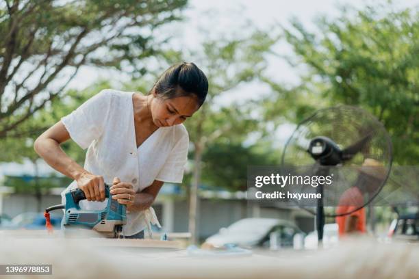 female carpenter cutting wood with jigsaw - 線鋸 個照片及圖片檔