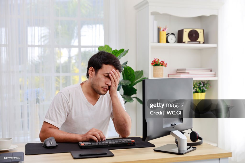 Tired Male Working At Home Using A Computer And Uses His Hand To Close ...