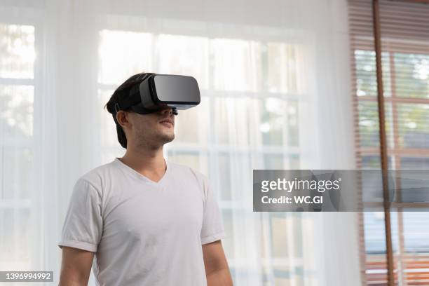 man puts on virtual reality headset or vr glasses at home - top prospects game ストックフォトと画像