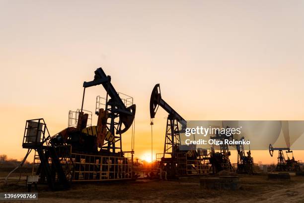 the silhouette of five oil pumps on a beautiful sunset sky with sun setting in between them.siberia. oil and gas production - oil platform bildbanksfoton och bilder