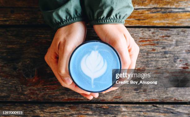 table top view of someone hands with a cup of blue latte coffee. - clitoria fotografías e imágenes de stock