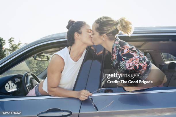 lesbian couple kissing through car window - lesbian date stock-fotos und bilder