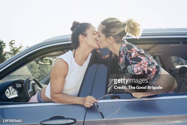 lesbian couple kissing through car window - lesbians kissing stock pictures, royalty-free photos & images