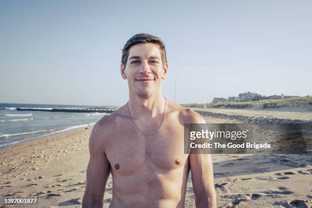 portrait of shirtless man standing on beach against clear sky - semi dress - fotografias e filmes do acervo