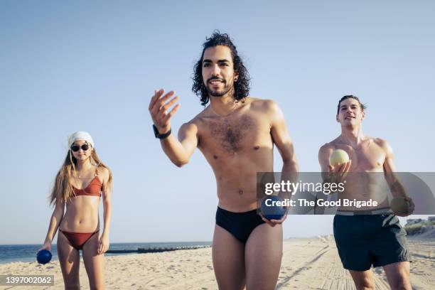 friends playing bocce ball against blue sky at beach - slip de bain de compétition photos et images de collection