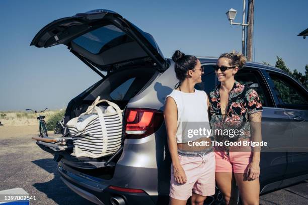 lesbian couple standing by car at beach - indian arrival stock pictures, royalty-free photos & images