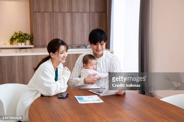 young asian couples with baby discuss financial planning together at home. - save our future babies stock pictures, royalty-free photos & images