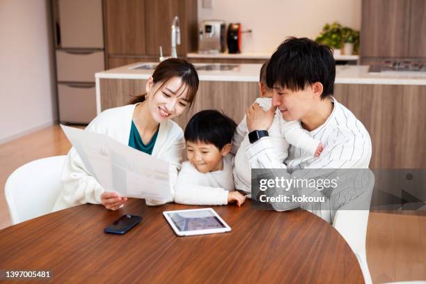 子供連れの若いアジア人カップルが自宅でホームファイナンスについて話し合う。 - 夫婦 ストックフォトと画像