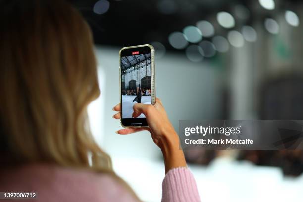 Guest records a model on her phone during the L'IDEE Woman show during Afterpay Australian Fashion Week 2022 Resort '23 Collections at Carriageworks...