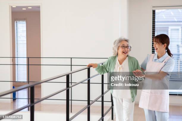 home caregiver  assisting a senior woman walking indoor - assisted living community stock pictures, royalty-free photos & images