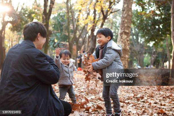 日没時に公園で落ち葉で遊んでいる子供たちとその父親。 - 父�の日　日本 ストックフォトと画像