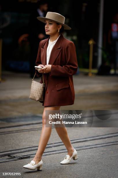 Guest wearing a boater hat, brown blazer and white shoes at Afterpay Australian Fashion Week 2022 on May 13, 2022 in Sydney, Australia.