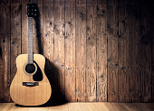 Acoustic guitar against blank wooden plank panel grunge background with copy space