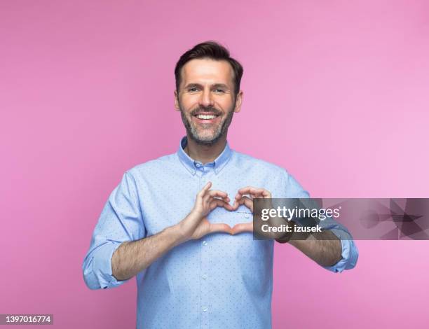 glücklicher mann gestikuliert herzzeichen - body language stock-fotos und bilder