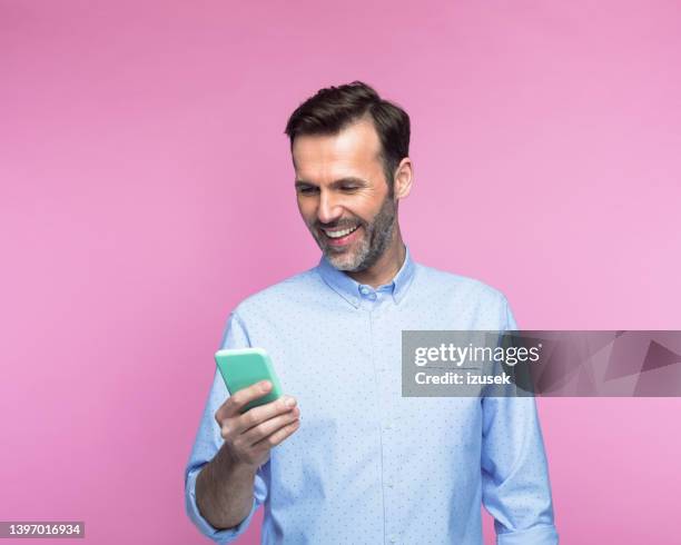 hombre feliz usando un teléfono inteligente - fondo con color fotografías e imágenes de stock