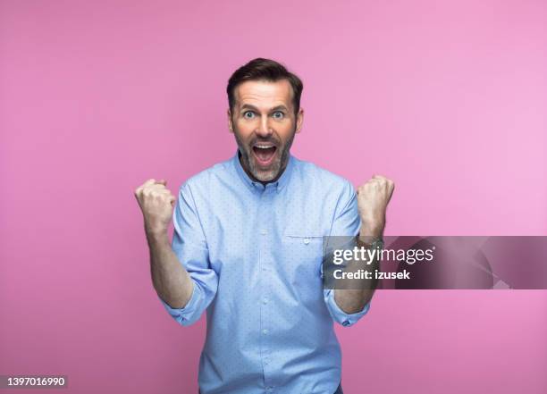 happy man with clenched fists - happy man pink background stock pictures, royalty-free photos & images