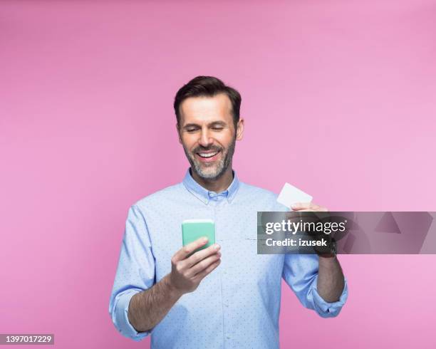 mann mit kreditkarte über smartphone - mann mit kreditkarte stock-fotos und bilder