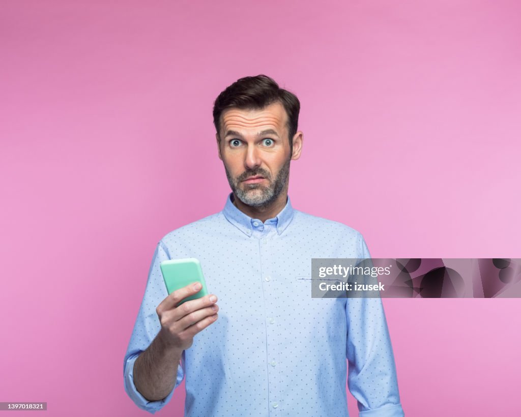 Shocked man holding mobile phone