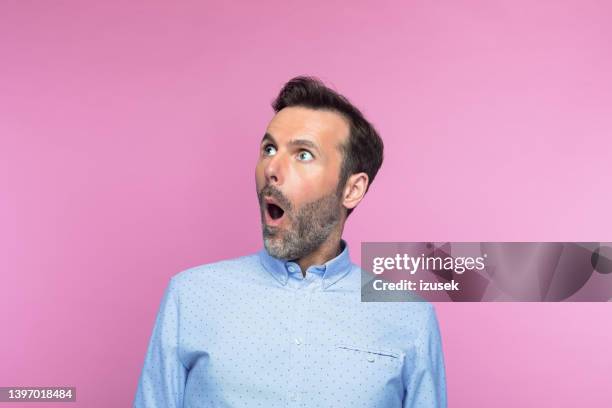 hombre adulto medio sorprendido mirando hacia arriba - shock fotografías e imágenes de stock