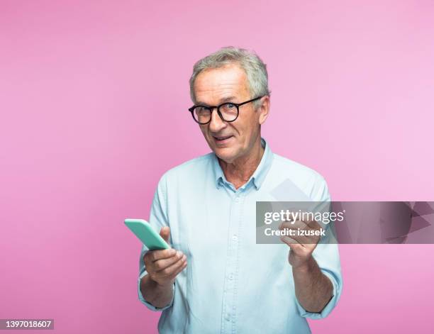 elderly man holding smart phone and credit card - shopping coloured background stock pictures, royalty-free photos & images